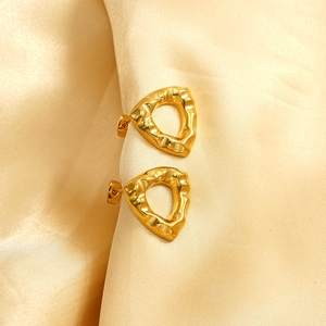Boucles d'oreilles triangle dorées à texture lave sur fond de soie élégante