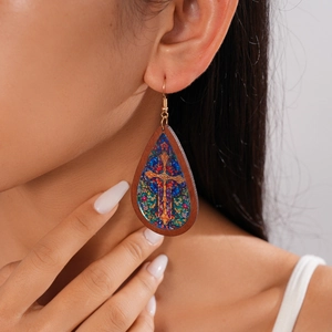 Close-up of bohemian wooden teardrop earrings with cross print on an elegant model