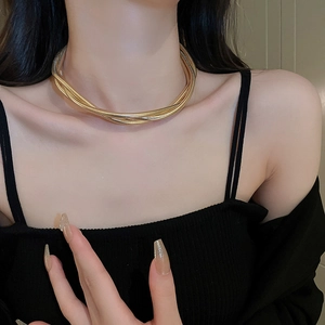Close-up of layered golden snake bone chain necklace on a model's neck for elegant styling