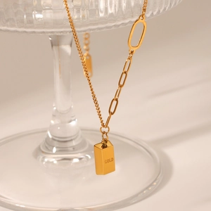 Detail of 18K gold-plated bar necklace featuring a GOLD engraving on a unique mixed link chain