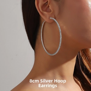 Macro side view of 8cm large silver hoop earring with sparkling white rhinestones on model
