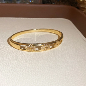 Gros plan d'un bracelet doré orné de trois motifs en T sertis de zircons étincelants
