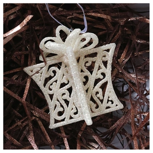 Close-up of glittery champagne cream gift box ornament with intricate hollow carving