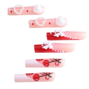 Pink and red press-on nails with 3D bows, pearl hearts, and cherry patterns in a set