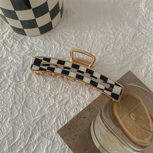 Detailed view of large black and white checkered hair claw clip with gold metal frame