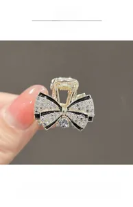 Detail of a small champagne gold bow hair claw with sparkling rhinestones and black enamel