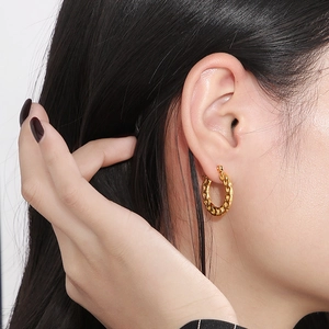 Close-up of golden chain-link hoop earring worn by a model for a chic style