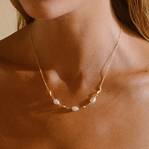 Macro shot of gold S925 sterling silver necklace featuring baroque pearls on a model