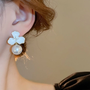 Detail of elegant floral pearl earring featuring white petals and square rhinestone on model