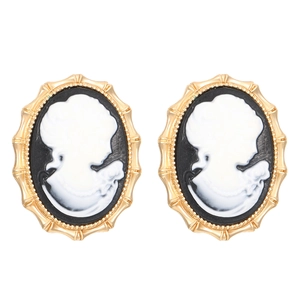 Close-up of vintage cameo earrings with white female profile on black background