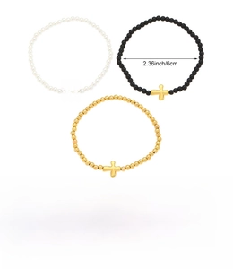 Dettaglio del set di tre braccialetti elastici con perline e ciondoli a forma di croce