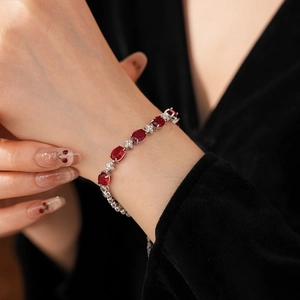 Macro detail of elegant oval ruby bracelet with zircon accents on female wrist