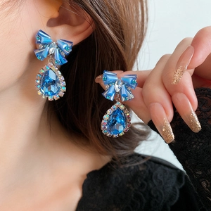 Detailed view of silver needle bowknot stud earrings with blue crystal water drop pendants