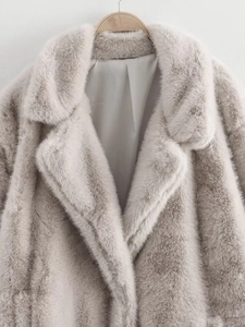 Détail de la texture d'un manteau en fausse fourrure gris clair à col en peluche