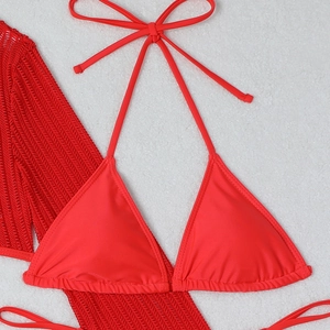 Detailed flat lay of red mesh drawstring bikini and matching crochet swimwear on white fur
