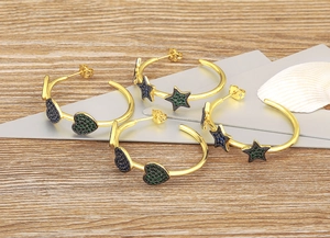 Detail of 18k gold plated C-shaped earrings with heart and star charms and zircon stones