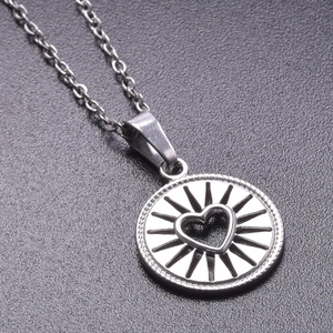Macro shot of silver stainless steel heart necklace with radial pattern on grey background