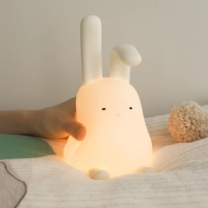Cute cartoon silicone lop-eared rabbit night light with warm glow on patterned blanket
