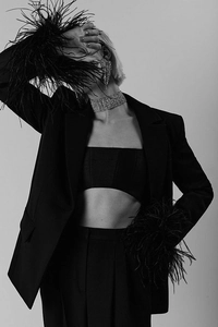 Close-up of black suit set featuring luxury feather cuffs and sparkling rhinestone trim