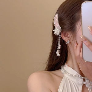 Detail of wing-shaped hair clip with pink crystals, pearls and long tassel on a model