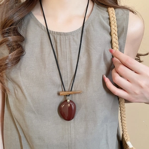 Detail of vintage mushroom pendant necklace with red resin bead on a long black cord