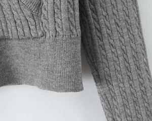 Detailed close-up of dark grey cable-knit texture and ribbed hem on hooded cardigan