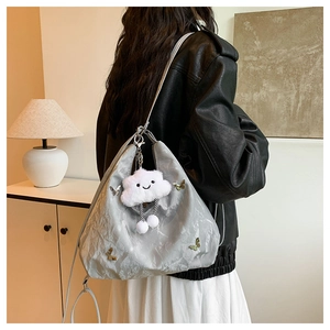 Detail of silver pleated nylon tote featuring a metal butterfly buckle and cute charm