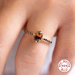Macro view of a S925 silver ring featuring an oval brown gemstone and black diamonds