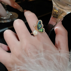 Detail of gold butterfly ring with iridescent shell wings and elegant pearl