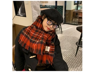 Close-up of red and black plaid vintage scarf with tassels and a black wool beret