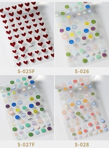Detailed macro view of 3D embossed nail art stickers with red hearts and colorful smiley faces