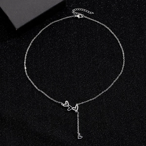 Macro shot of silver Y-shaped necklace featuring triple interlocking pavé hearts with tassel
