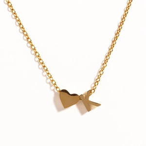 Detailed macro view of 18k gold heart and K letter pendant on stainless steel chain