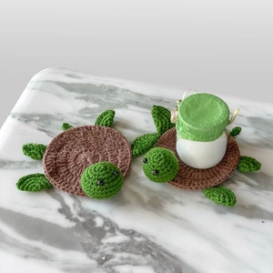 Close-up of handmade crochet turtle coasters protecting a table under a glass jar