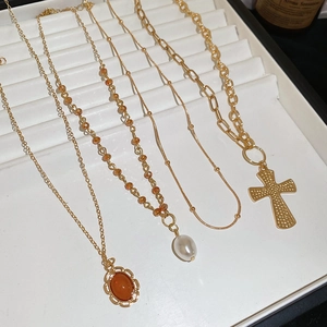 Close-up of gold cross pendant and pearl crystal necklaces on a white jewelry tray