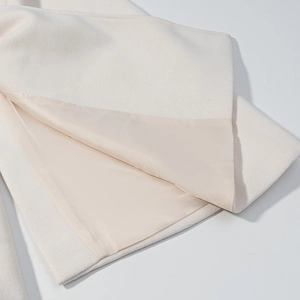 Detail showing the inner lining stitched to the cream wool-blend fabric of the coat
