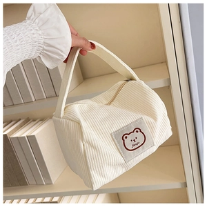 Detail of cream corduroy handbag with a cartoon bear patch and soft texture