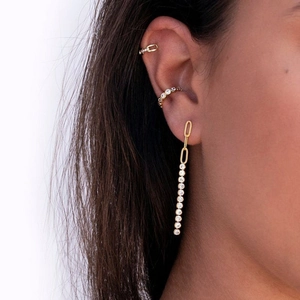 Detail of gold chain earrings with sparkling zircons and minimalist ear cuff set on model