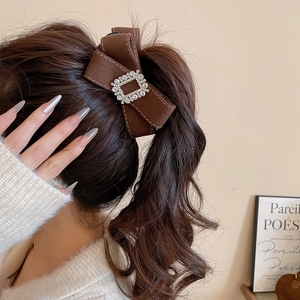 Close-up of velvet bow hair clip with rhinestone center on a high ponytail hairstyle