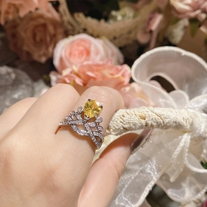 Macro shot of silver crown ring with yellow pear-cut gemstone worn on finger