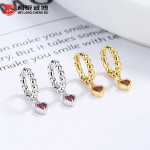 Close-up of beaded hoop earrings with red heart charms in silver and gold finishes