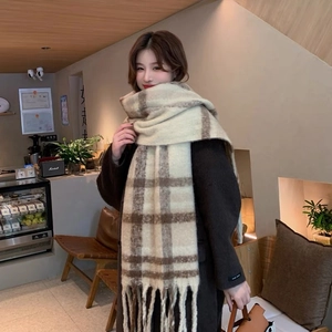 Close-up of thick beige and coffee plaid scarf with soft knit texture and long fringe