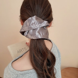 Detailed back view of a grey oversized satin scrunchie styled on long curly hair