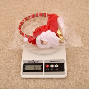 Detailed view of red plush Christmas earmuffs with Santa doll being weighed on a scale
