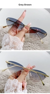 Close-up of frameless grey brown gradient cat eye sunglasses with metal diamond-set F detail