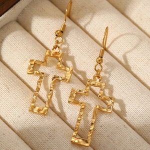 Elegant gold hollow cross earrings with textured finish on a beige jewelry cushion