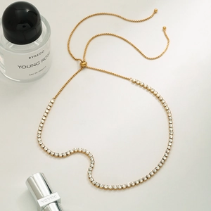 Collier en acier inoxydable doré avec zircons et fermoir réglable sur marbre