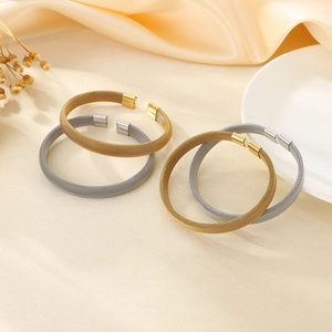 Dettaglio di bracciali a rete metallica intrecciata in oro e argento su seta