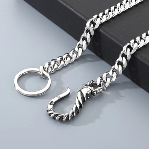 Detail of heavy silver Cuban link pants chain with vintage dragon head clasp on gray background