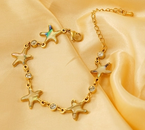 Detailed macro of golden starfish bracelet with shell inlay and sparkling zircon crystals